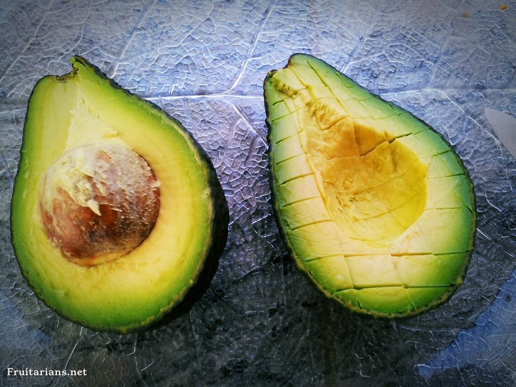 Cut an avocado in half, moving the knife in a circle, reaching to the central seed, and then separate the pieces, leaving the seed in one half.